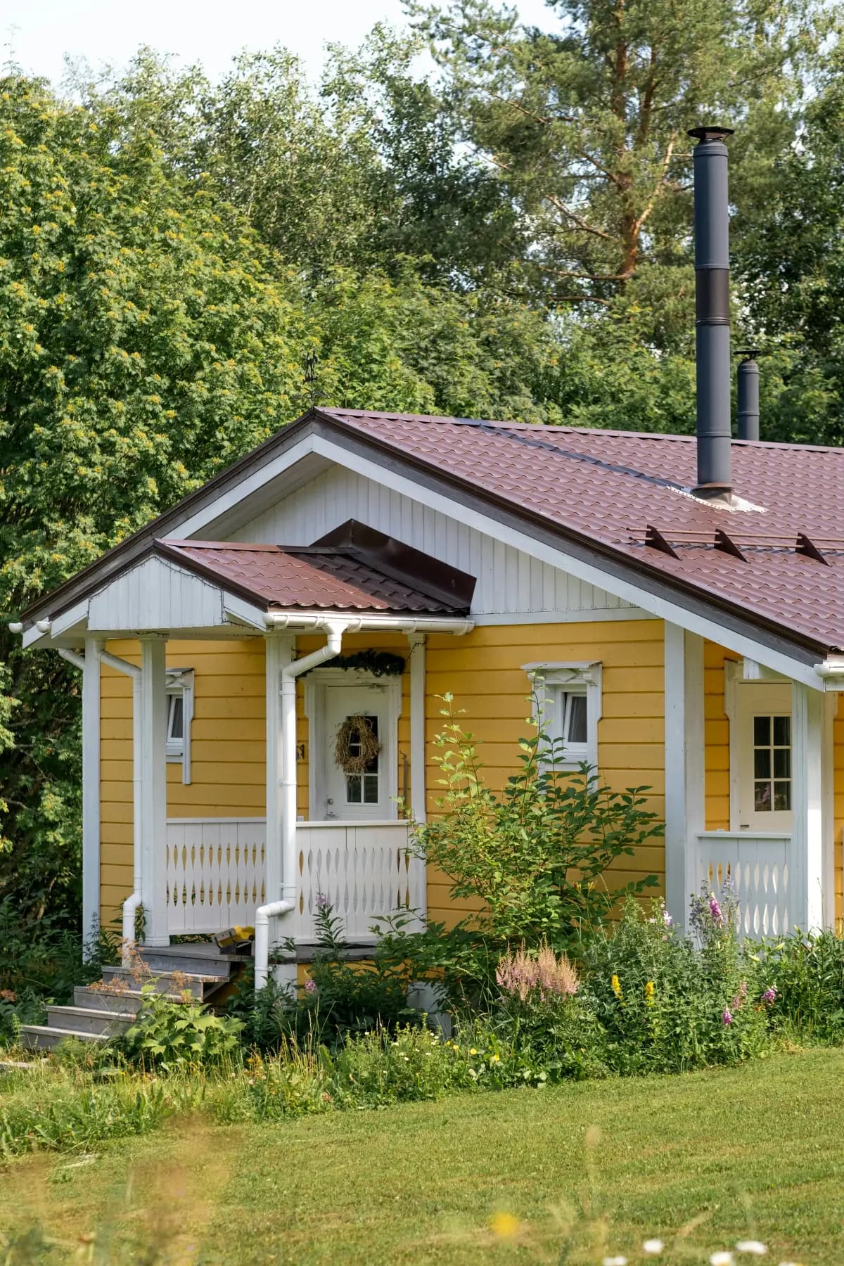 Gult landsted med veranda og frodig hage i varmt lys